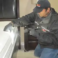 Bed bug inspection technician checking a mattress and bed frame for signs of infestation in St Paul, MN