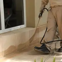 General pest control technician spraying exterior perimeter around a home in St Paul, MN