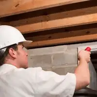 Termite inspection technician checking a basement wall and framing for termite activity in St Paul, MN